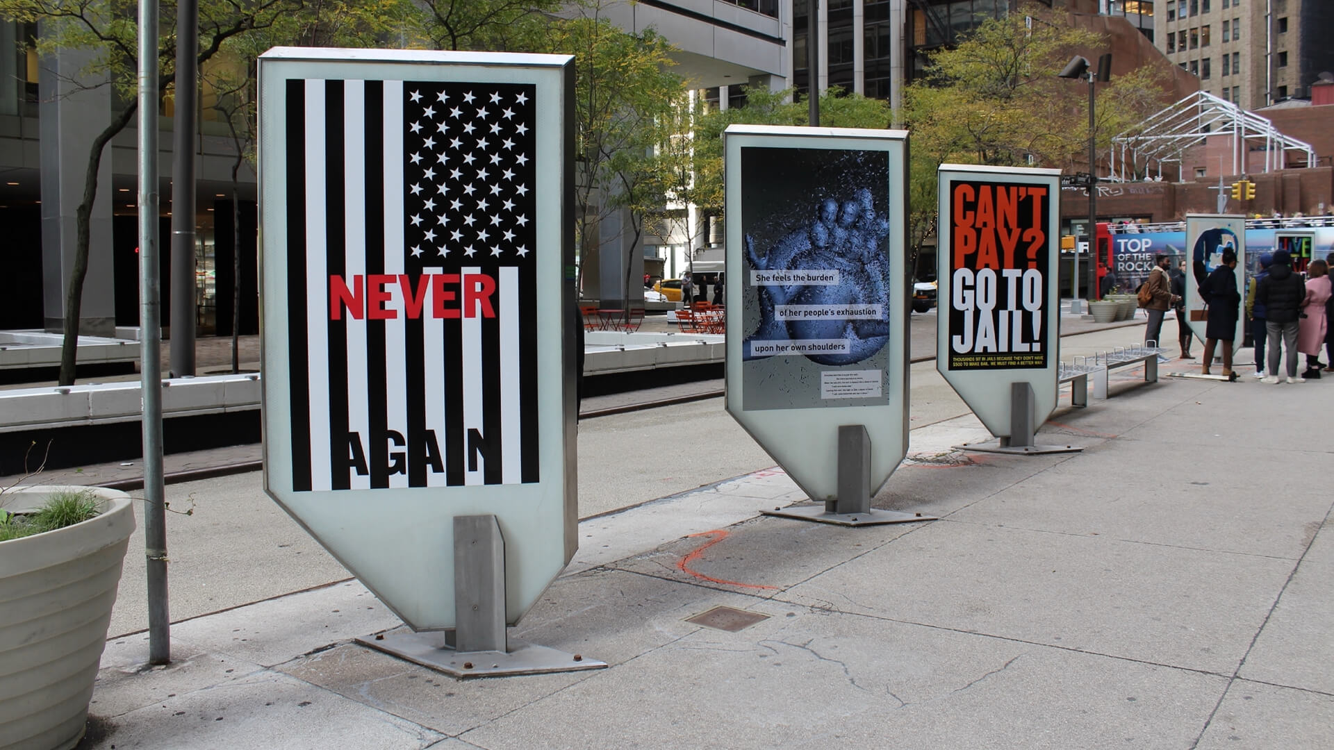 sidewalk lined with posters recedes into the distance