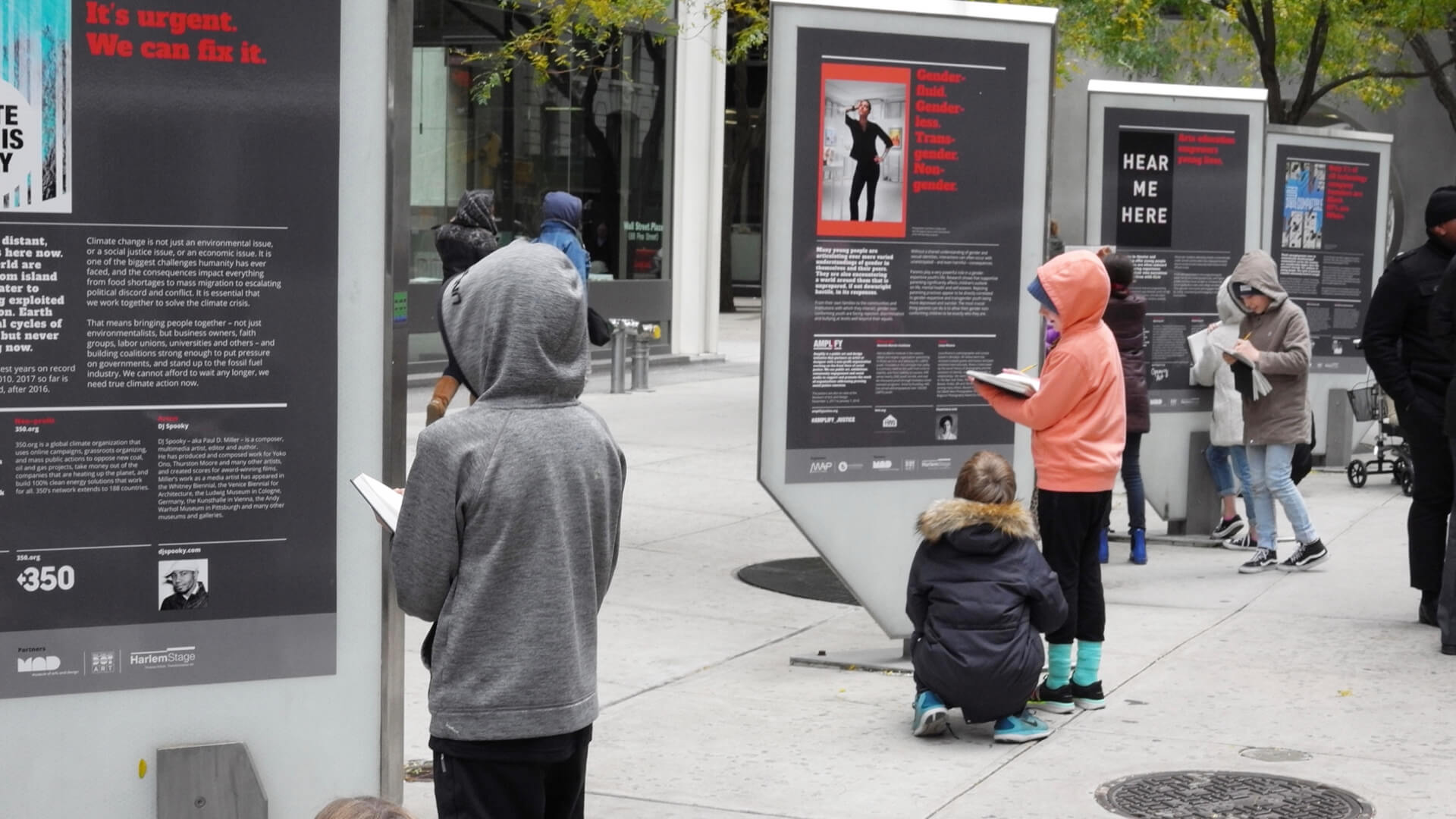 students survey the streetscape exhibition taking notes in their notebooks